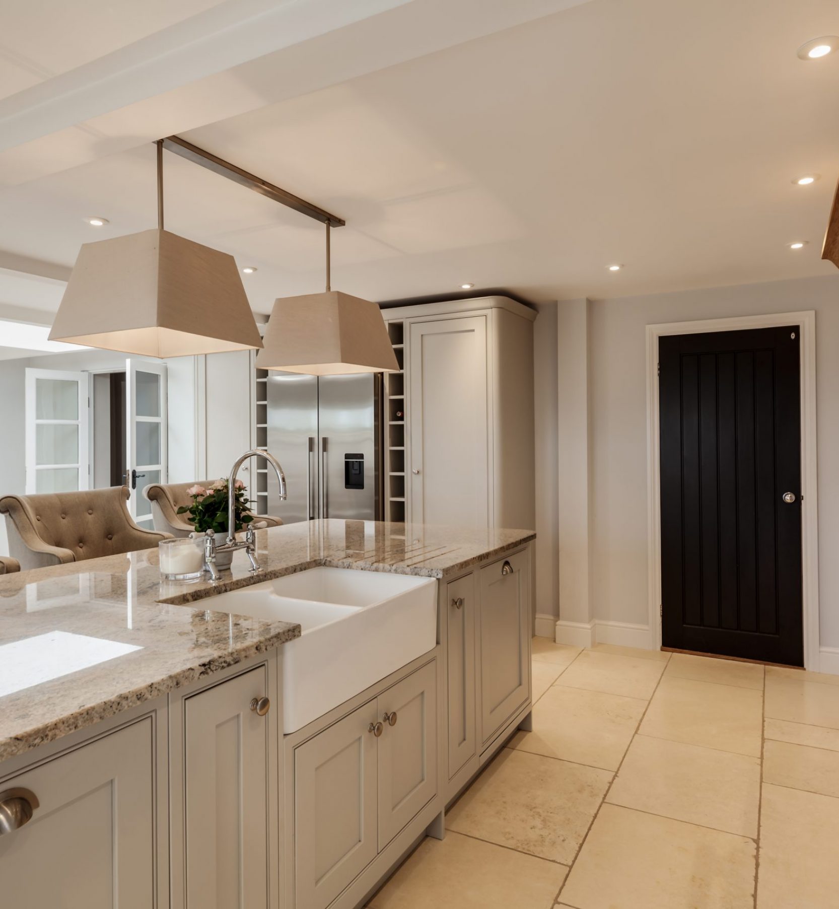 Beautiful luxurious traditional style modern kitchen Exceptional luxurious chic fitted kitchen with built in appliances including range cooker and marble granite counter tops, butler style sink and upholstered stools against an island peninsular unit decorated in shades of white and grey